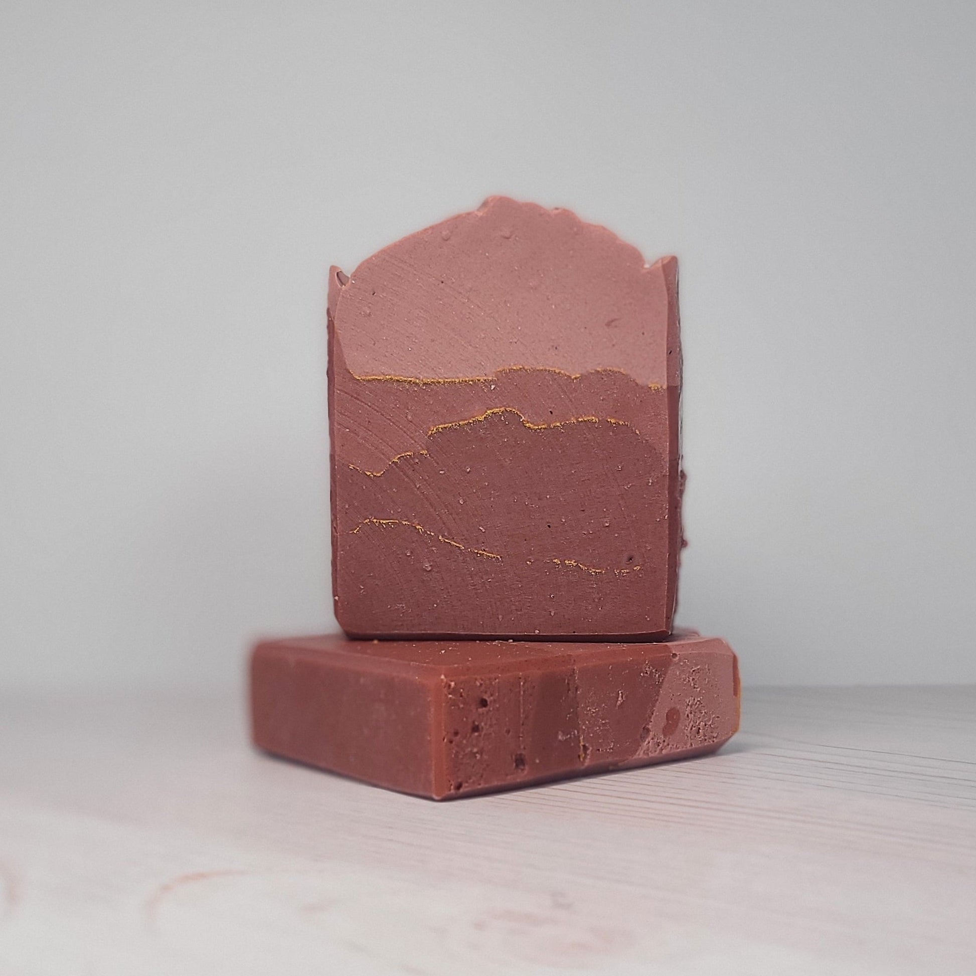 Two stacked bars of brown soap on a light gray background